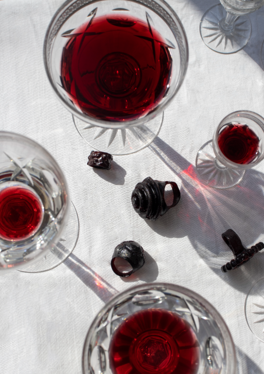 Glimmers of Mystery: Exposed Rings Amidst Wine or Blood-filled Glasses